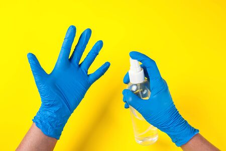 Hands in blue medical gloves holding bottle with antiseptic spray. Medicine and healthcare conceptの写真素材