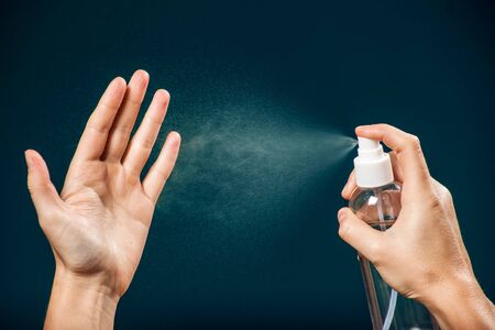 Using antibacterial spray for hands. People, healthcare and hygiene concept. Coronavirus protection.