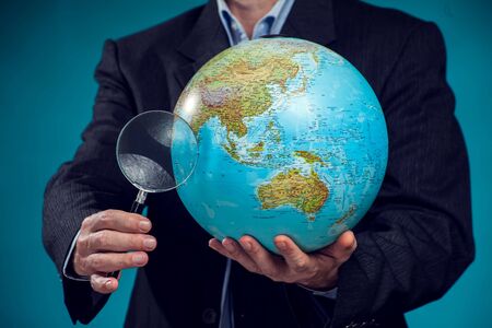 Businessman in suit holding globus and magnifier in hands. Environment protection, travel and idea...
