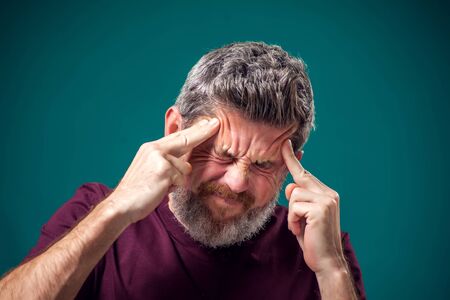 A portrait of bearded man in red t-shirt thinking hard or have headache. People, emotions and health...