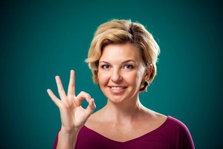 Woman with short blond hair showing okay gesture. People,lifestyle and emotions conceptの写真素材