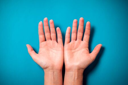 Woman's empty palms on blue background. Close-up shot. の写真素材