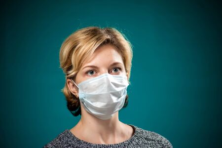 A portrait of woman with short blond hair with medical face mask. People, medicine and healthcare concept. Coronavirus protectionの写真素材