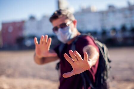 Man with medical face mask showing stop gesture outdoor. People, healthcare and medicine conceptの写真素材
