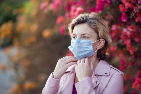 A portrait of woman with short blond hair with medical face mask outdoor. People, healthcare and medicine concept.の写真素材