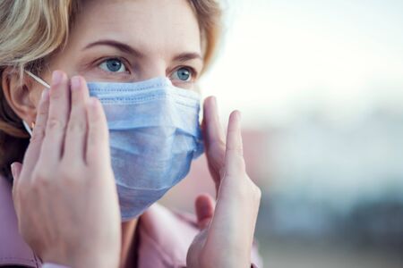 A portrait of woman with short blond hair with medical face mask outdoor. People, healthcare and...