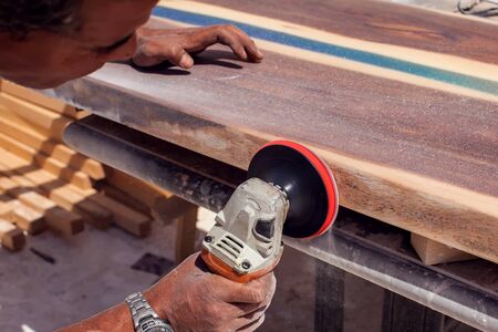A handyman grinding wooden board outdoor. の写真素材