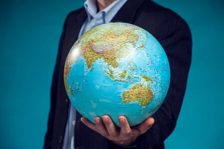 Businessman in suit holding globus in hands. Environment protection, travel and idea concept. Close up.の写真素材