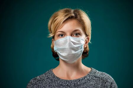 A portrait of woman with short blond hair with medical face mask. People, medicine and healthcare concept. Coronavirus protectionの写真素材