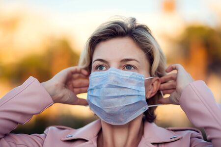 A portrait of woman with short blond hair with medical face mask outdoor. People, healthcare and medicine concept.の写真素材
