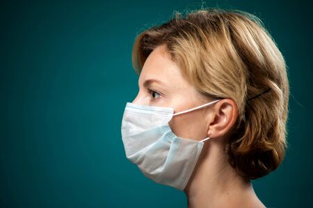 A portrait of woman with short blond hair with medical face mask. People, medicine and healthcare...