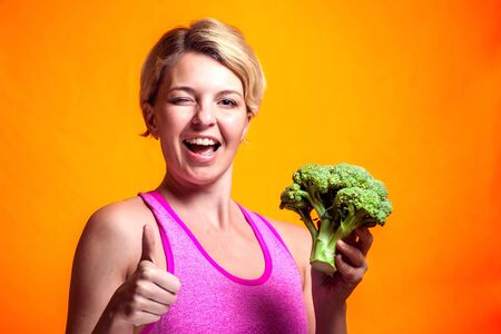 A portrait of smiling woman holding broccoli showing thumb up gesture. Nutrition, healthcare and diet conceptの写真素材