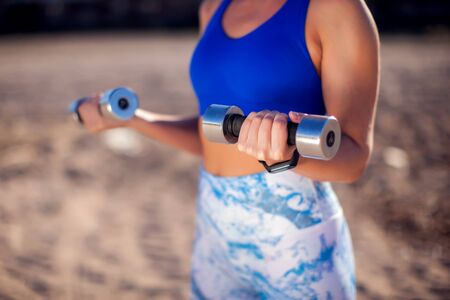 Woman with short blond hair training with dumbbells outdoor. People, fitness and healthcare conceptの写真素材