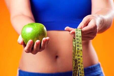Woman in sportswear holding apple and meter. People, fitness and dieting conceptの写真素材