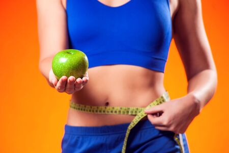 Woman measuring waist and holding apple. People, fitness and dieting conceptの写真素材
