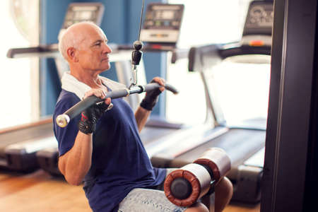 Senior man in the gym training back muscles. People, health and lifestyle concept