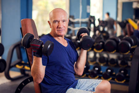 Senior man in the gym training with dumbbells. People, health and lifestyle conceptの写真素材