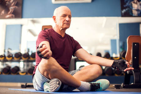 A portrait of bald senior man doing relaxation exercise in the gym. People, healthcare and lifestyle conceptの写真素材