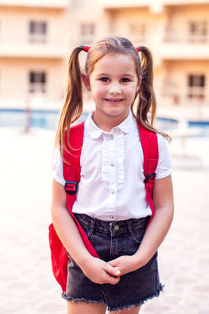 Back to school. Pupil girl with backpack staying outdoorの写真素材