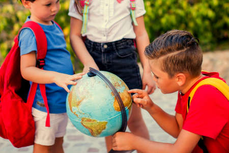Back to school. Pupils looking at globe outdoor. Geography and education concept