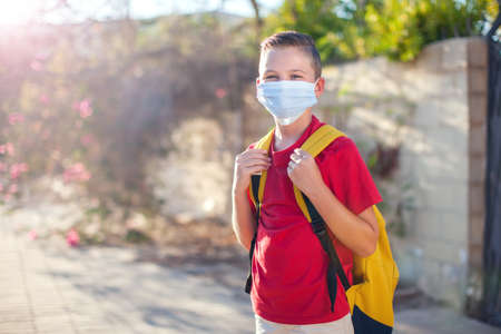 Pupil with medical mask on face and backpacks outdoor. Education during coronavirus time. Children and healthcare. Back to school.の写真素材
