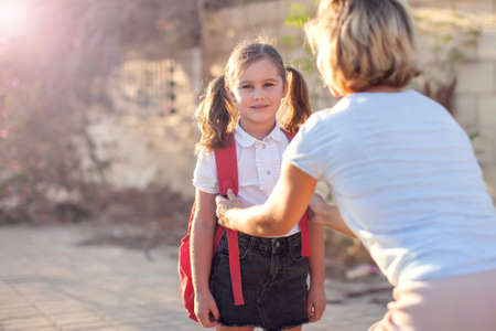Mother meeting pupil from the school. Back to school. Parent and children relationships.