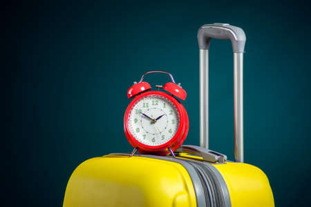 Alarm clock on luggage. Travel and holiday concept. Studio shotの写真素材