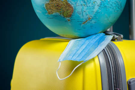 Globe with medical face mask on luggage. Travel and coronavirus concept. Studio shotの写真素材