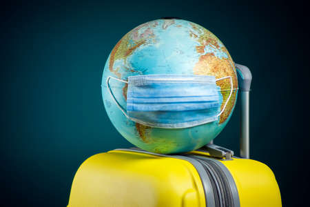 Globe with medical face mask on luggage. Travel and coronavirus concept. Studio shotの写真素材