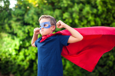 Superhero kid boy against green background outdoor. Childhood, success and and power conceptの写真素材