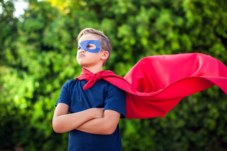 Superhero kid boy against green background outdoor. Childhood, success and and power conceptの写真素材