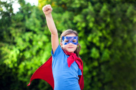 Superhero kid girl against green background outdoor. Childhood, success and and power conceptの写真素材