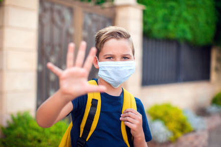 Pupil boy with face mask staying outdoor. Back to school in coronavirus pamdemidの写真素材