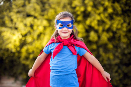 Superhero kid girl against green background outdoor. Childhood, success and and power conceptの写真素材