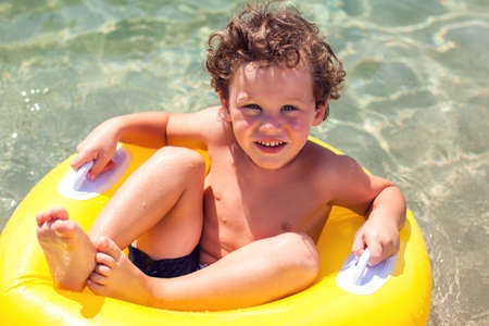 Kid on beach with swimming circle. Boy swimming in sea. Children and holiday conceptの写真素材