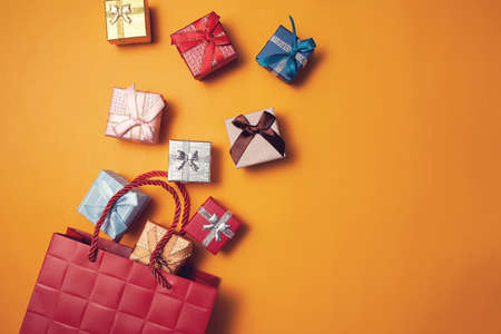 Gift boxes falling into gift bag on yellow background. Celebration, party and shopping conceptの写真素材
