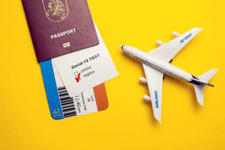 Coronavirus and safety travel concept, Covid-19 test with "Negative" mark, airline ticket, passport and plane on yellow backgroundの写真素材