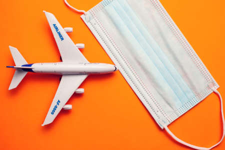 Savety travel during covid-19 pandemic. Plane with medical face mask on yellow background. Coronavirus Alert.の写真素材