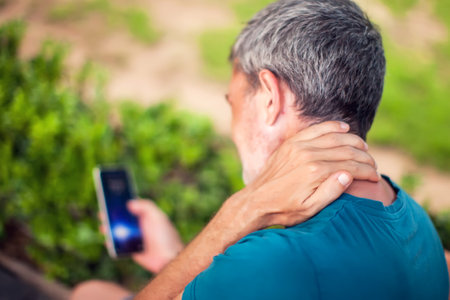 Neck pain using smartphone outdoor. Healthcare, lifestyle and technology conceptの写真素材