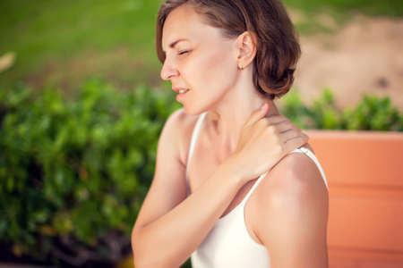 Neck pain. Woman feeling neck or shoulder ache outdoor. Healthcare and lifestyle conceptの写真素材