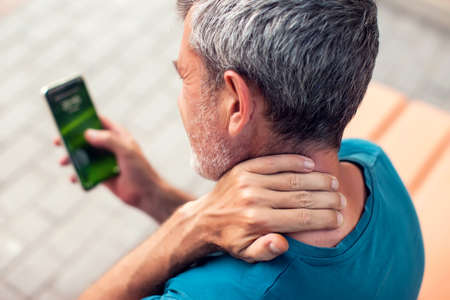 Neck pain using smartphone outdoor. Healthcare, lifestyle and technology conceptの写真素材