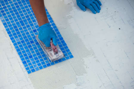 Worker laying tile in the pool. Pool repairing work.の写真素材