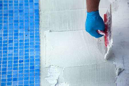 Worker laying tile in the pool. Pool repairing work.の写真素材