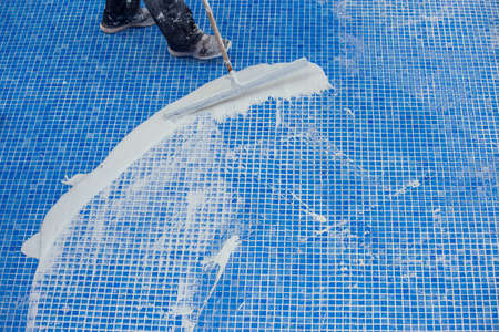 Worker covering seames on the tile in the pool. Pool repairing workの写真素材