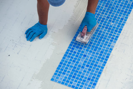 Worker laying tile in the pool. Pool repairing work.の写真素材