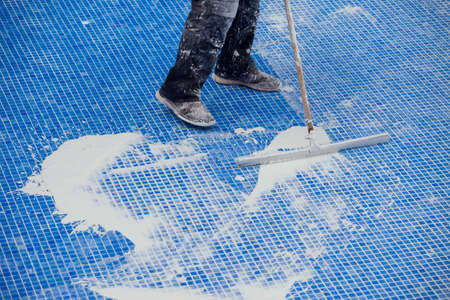Worker covering seames on the tile in the pool. Pool repairing workの写真素材