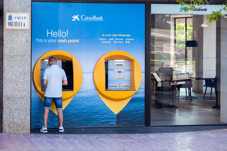 Torrevieja, Spain, 24 of May 2021, Man using cash machine of La Caixa Bank. Costa Blanca, Spainのeditorial素材
