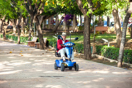 Torrevieja, Spain, 05/24/2021, Disabled senior man using electric wheelchair in the park. Lifestyle and independence of disabled peopleのeditorial素材