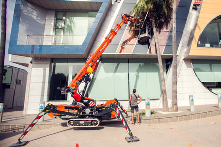 Torrevieja, Spain, 15.06.2021. The worker cleaning windows at mobile elevating work platform, Spain, Costa Blancaのeditorial素材