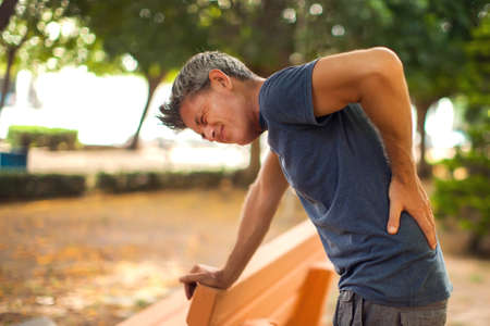 Man with back pain in the park. Healthcare and medicine conceptの写真素材